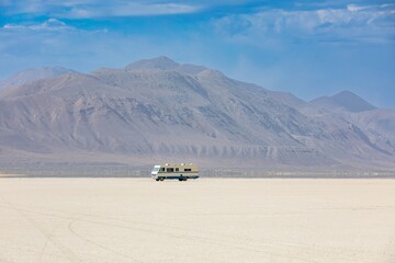 A lone RV sits on the vast, dry expanse of the Black Rock Desert in Nevada, USA. The vehicle is exploring the remote landscape.  Gerlach, Nevada, USA
