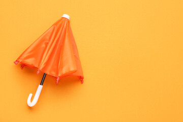 Mini orange umbrella on color background