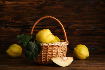 Wicker basket with sweet ripe quinces and leaves on wooden background