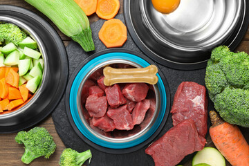 Pet food. Fresh beef in feeding bowl and chew bone among products on wooden table, flat lay