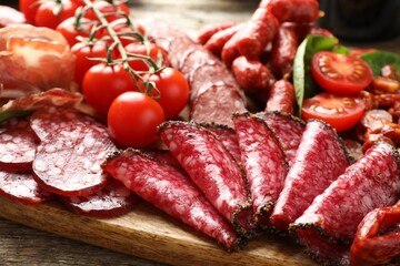 Different smoked sausages, ham and tomatoes on table, closeup