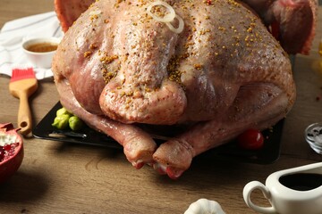 Whole raw turkey with ingredients for marinade on wooden table, closeup