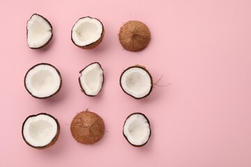 Pieces of cracked coconuts on pink background, flat lay. Space for text