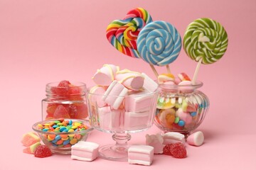 Tasty marshmallows in glass dessert bowl and candies on pink background
