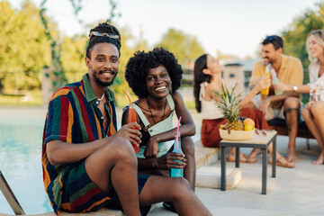 Obraz premium Young couple enjoying drinks by the pool at a summer party