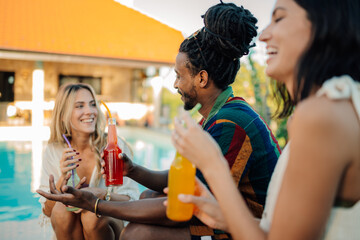 Friends enjoying drinks by the poolside, celebrating summer holidays