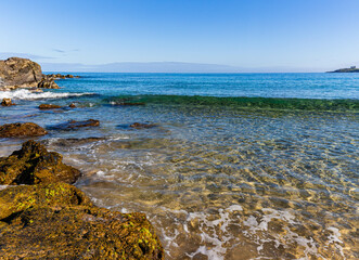 Waves Washing Over Boulders From Makaluapuna Point on Fleming Beach With Molokai Island Across...