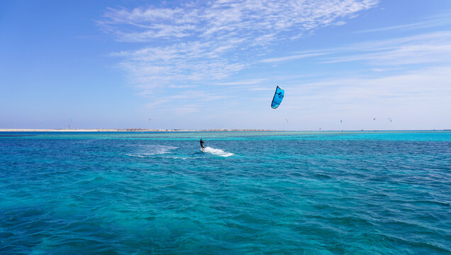 A kitesurfer above the clear waters of the Red Sea on a sunny summer day. With a bright blue sky and turquoise sea, this scene is perfect for travel, adventure, and watersports content