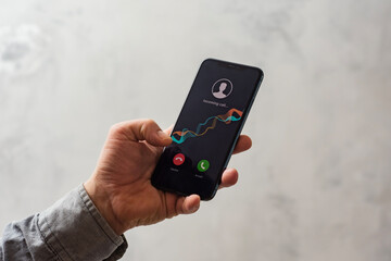 Close-up of a hand holding a smartphone with an incoming call screen. Display shows Incoming call...