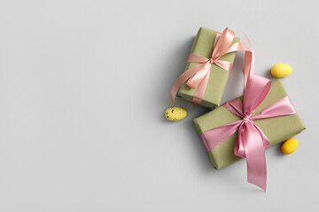 Easter eggs with gift boxes on grey background