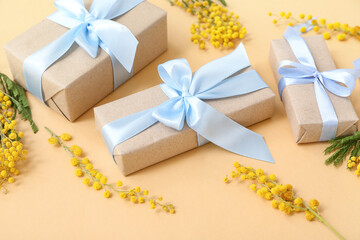 Elegant wrapped gift boxes with mimosa flowers on yellow background