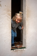 A young child playfully emerging from a small window, smiling joyfully