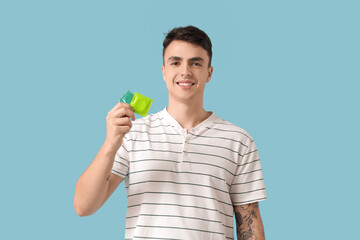 Happy young man with condoms on blue background