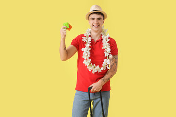 Happy young man with condoms on yellow background
