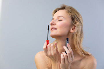 Captivating Moment: A Barefaced Woman Applying Mascara with Graceful Focus on Personal Beauty in a...