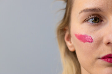 Close-Up of a Young Woman with Pink Lipstick Applying Makeup to Her Cheek for a Chic, Artistic Look...
