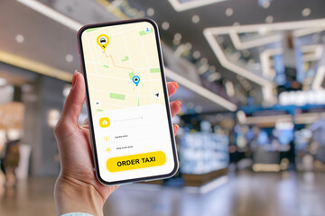 Woman using taxi app on smartphone, ordering taxi in shopping mall.
