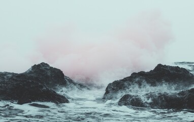 Misty ocean scene with dark rocks and soft pink sky.
