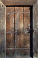 Ancient wooden door closed with a padlock.