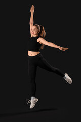Obraz premium Sporty young woman jumping on black background