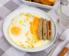 Homemade hearty breakfast - fried eggs with frankfurter and onion. Dish is decorated by spring of cilantro parsley