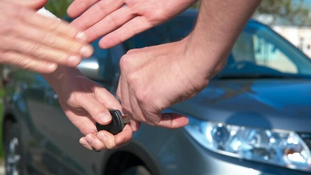 Lady getting car key from salesman. A view of lady hands takes the key from salesman by the new car.