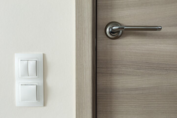 Door handle and white lighting switches on wall