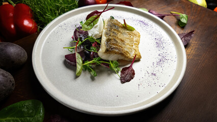 Fried pike perch fillet with herbs and vegetables on a wooden cutting board