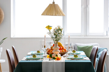 Beautiful table setting with citrus fruits and burning candles in living room