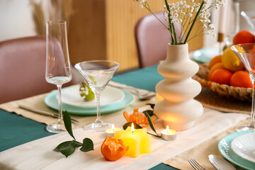 Burning candles and citrus fruits on served table. Closeup