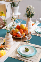 Stylish table setting with fresh citrus fruits and flowers in room. Closeup