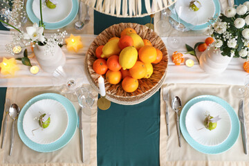 Stylish table setting with fresh citrus fruits and flowers in room. Top view