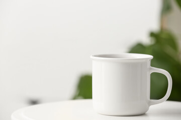 White mug on table on blurred background. Closeup