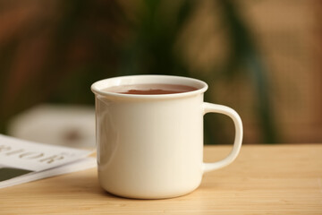 Mug of hot tea on wooden table on blurred background. Closeup
