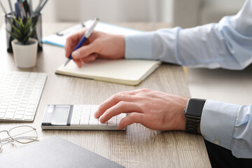 Fototapeta premium Male hands working with calculator in office. Closeup