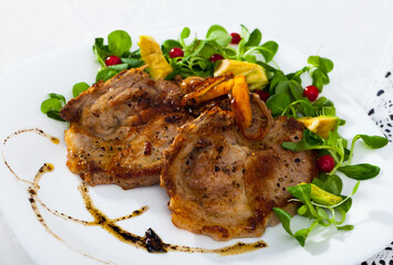 Tasty cooked fried pork chops with avocado, greens and berries at plate