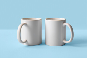 Empty ceramic mugs on blue background