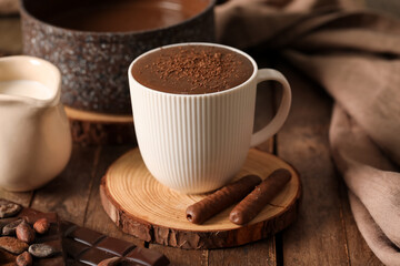 Cup of tasty melted chocolate on wooden table. Closeup