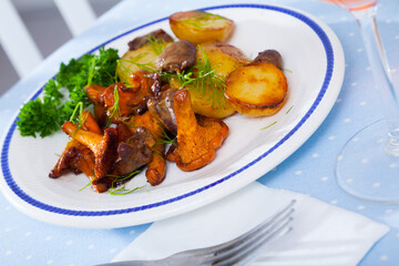 Fried chanterelles with baked potatoes and chicken hearts garnished with fresh greens
