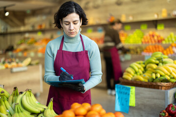 During inventory, female employee counts and records quantity of goods in paper report, checks data of invoice from supplier, checks goods at point of retail sale.
