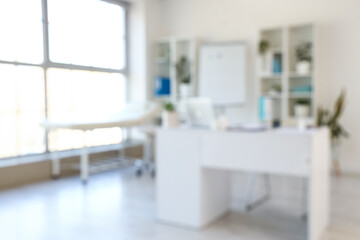 Blurred view of medical office with doctor's workplace and shelf units