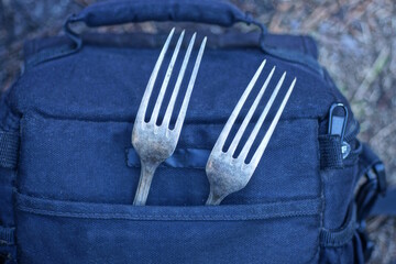 two gray metal old forks in black pocket of bag on summer street