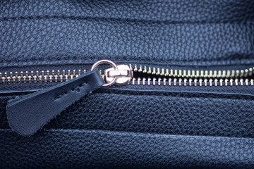 one gray open zip fastener on a leather black bag
