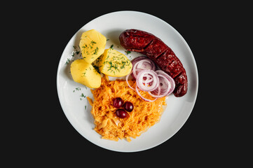 Tasty traditional Food plate isolated on black background, potatoes with cabbage and sausage