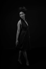 Full length black and white portrait of pretty curly woman in black dress