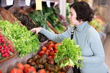 Woman carefully choosing salad while standing in supermarket