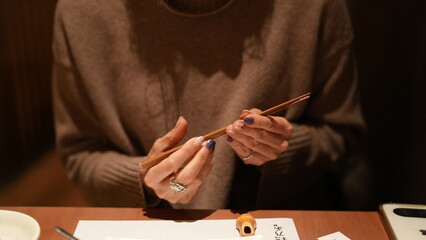 女性が箸を持ち食事をする