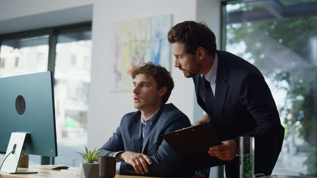 Serious mentor giving advice to manager in modern office. Colleagues working