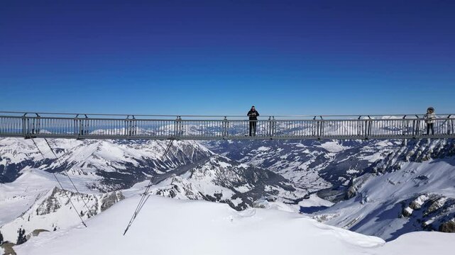 Glacier, Switzerland - 15 February 2025 :Panoramic Aerial View of Glacier 3000 with Alpine Peaks, Suspended Bridge (Peak Walk), and a Man while Flying a Drone.