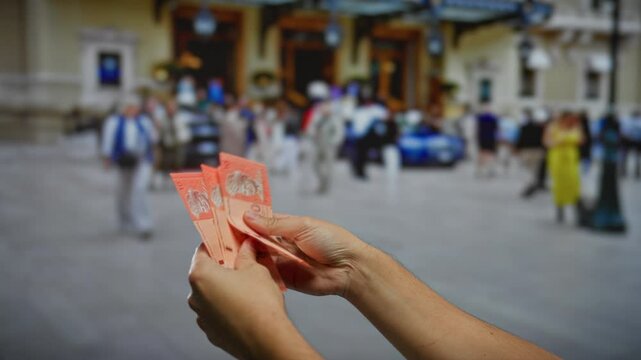 Man holding malaysian ringgit on busy urban street with people walking in the background, capturing the essence of outdoor city life and financial transactions.